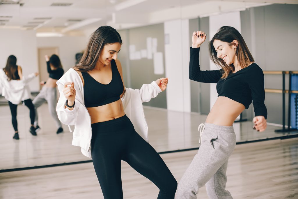 שתי נשים צעירות עושות תנועות ריקוד בחדר סטודיו